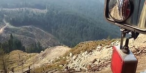 Peterbilt log truck coming off steep cliff .